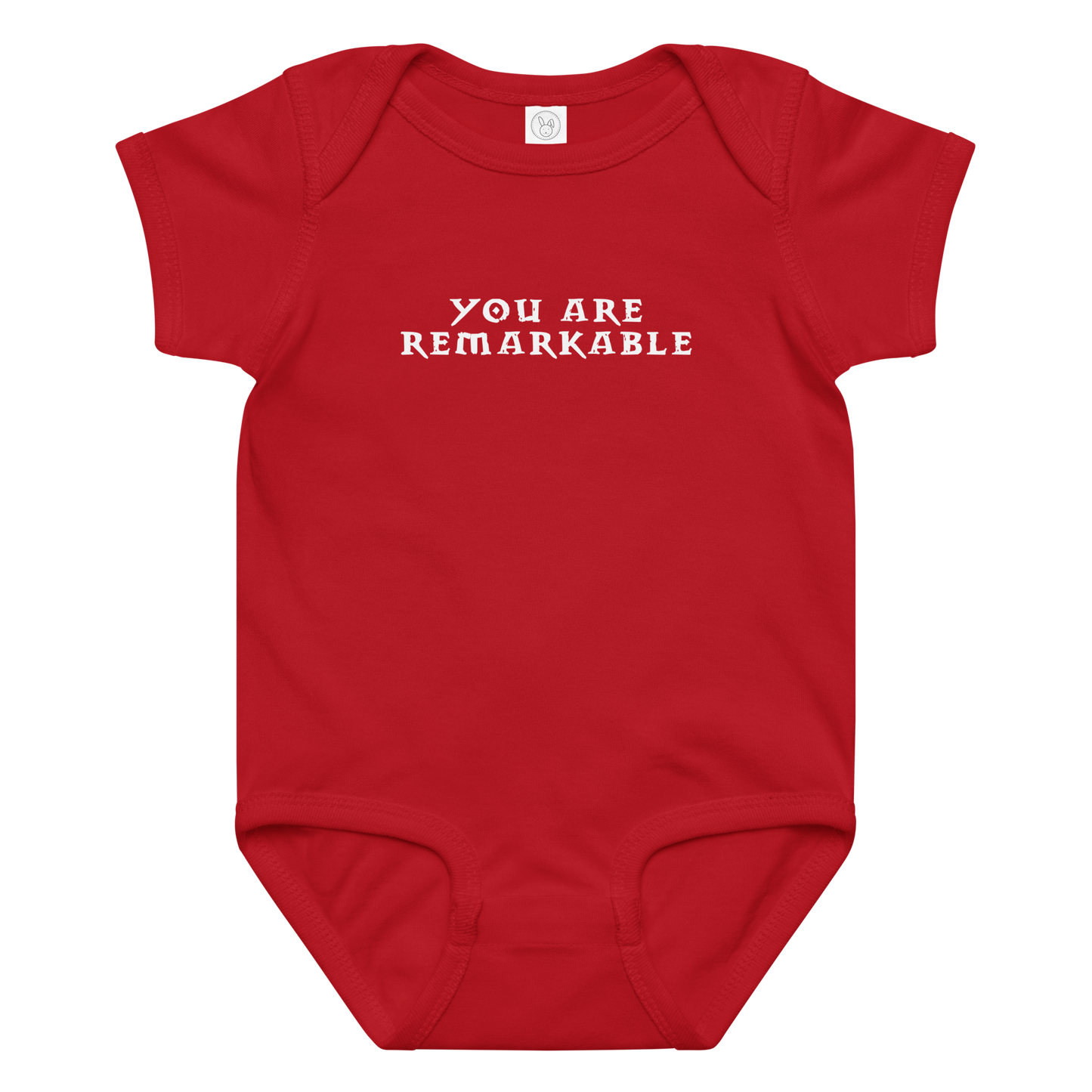 "You are remarkable" printed on a red baby jersey bodysuit laying on a flat surface amongst other clothes