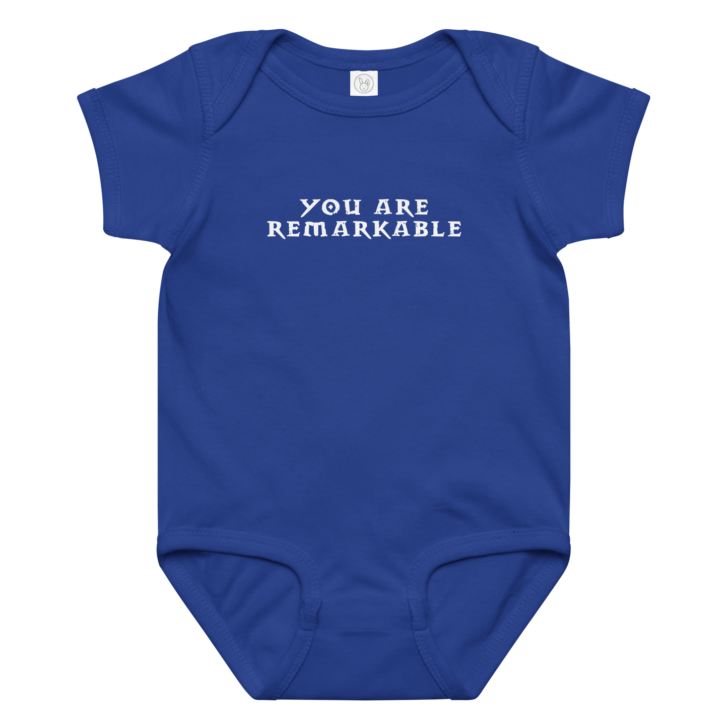 "You are remarkable" printed on a royal baby jersey bodysuit laying on a flat surface amongst other clothes