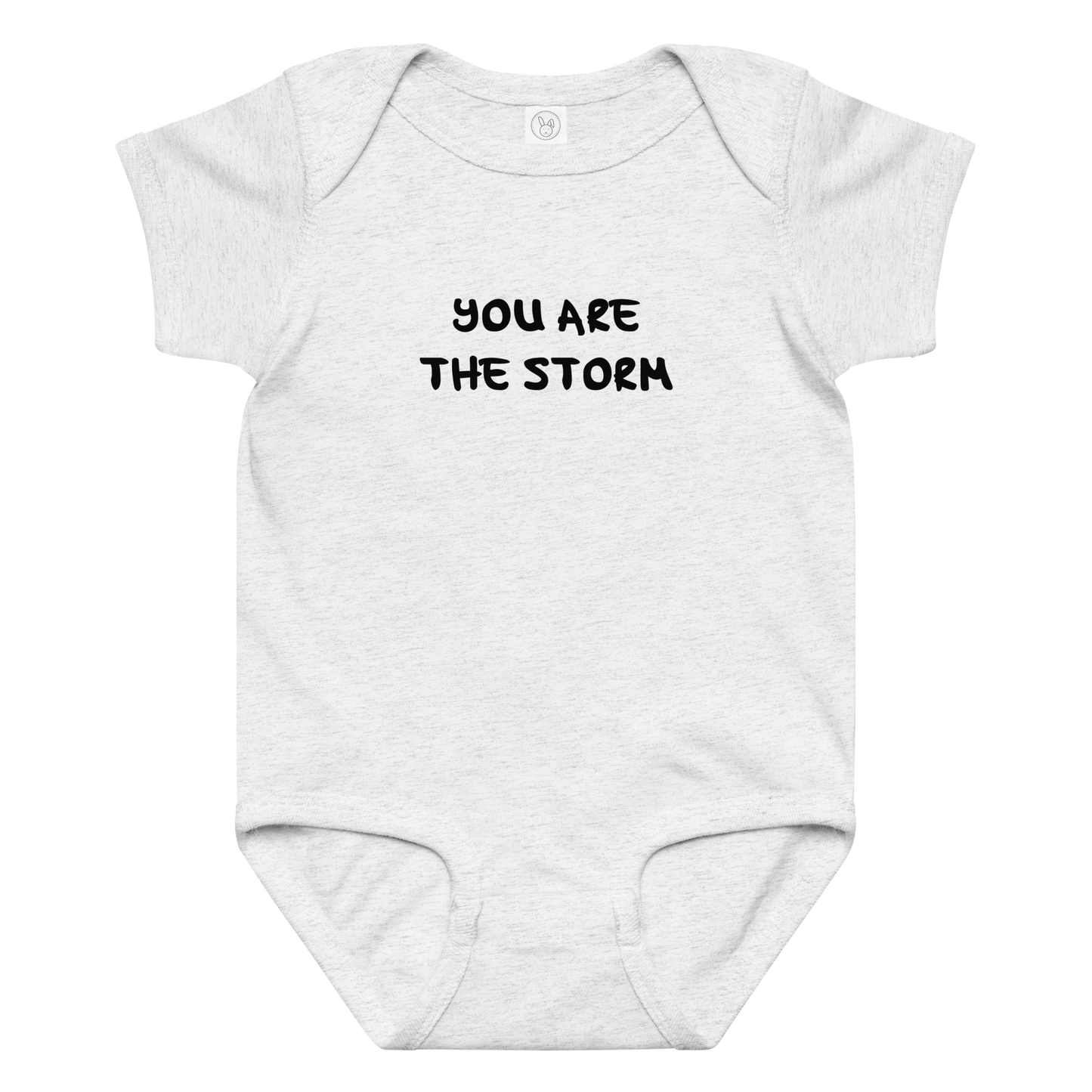 "You are the storm" printed on a ash baby jersey bodysuit laying on a flat surface amongst other clothes