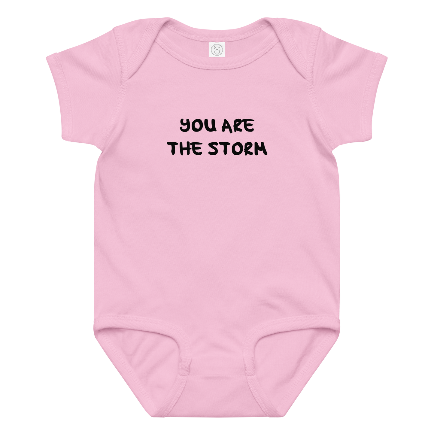 "You are the storm" printed on a pink baby jersey bodysuit laying on a flat surface amongst other clothes