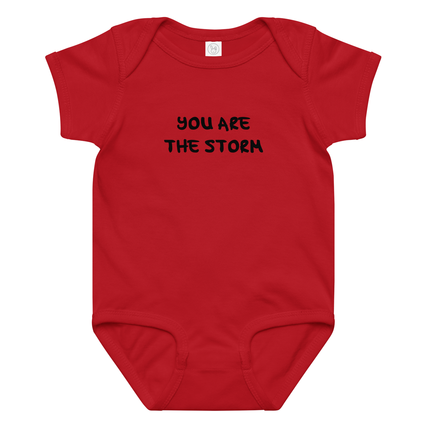 "You are the storm" printed on a red baby jersey bodysuit laying on a flat surface amongst other clothes