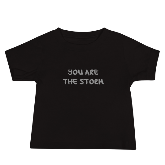 "You are the storm" printed on a black baby jersey short sleeve tee laying on a flat surface
