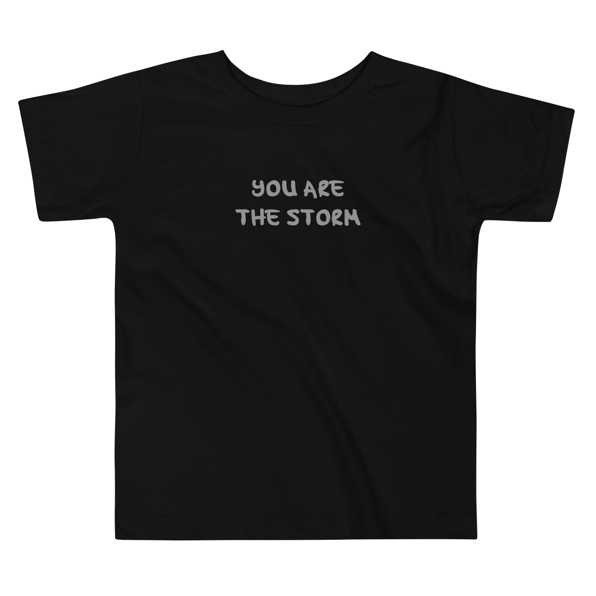 "You are the storm" printed on a black toddler short sleeve tee laying on a flat surface