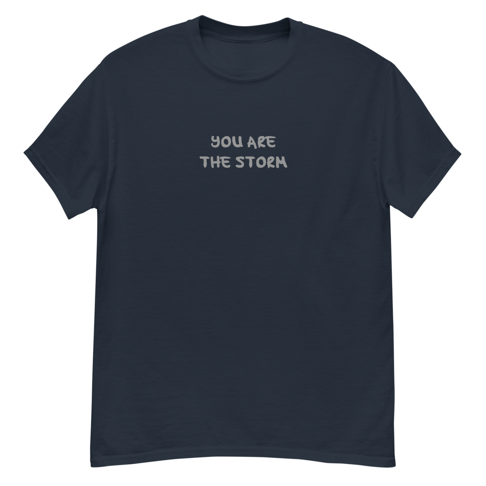 "You are the storm" printed on a navy unisex classic tee laying on a flat surface