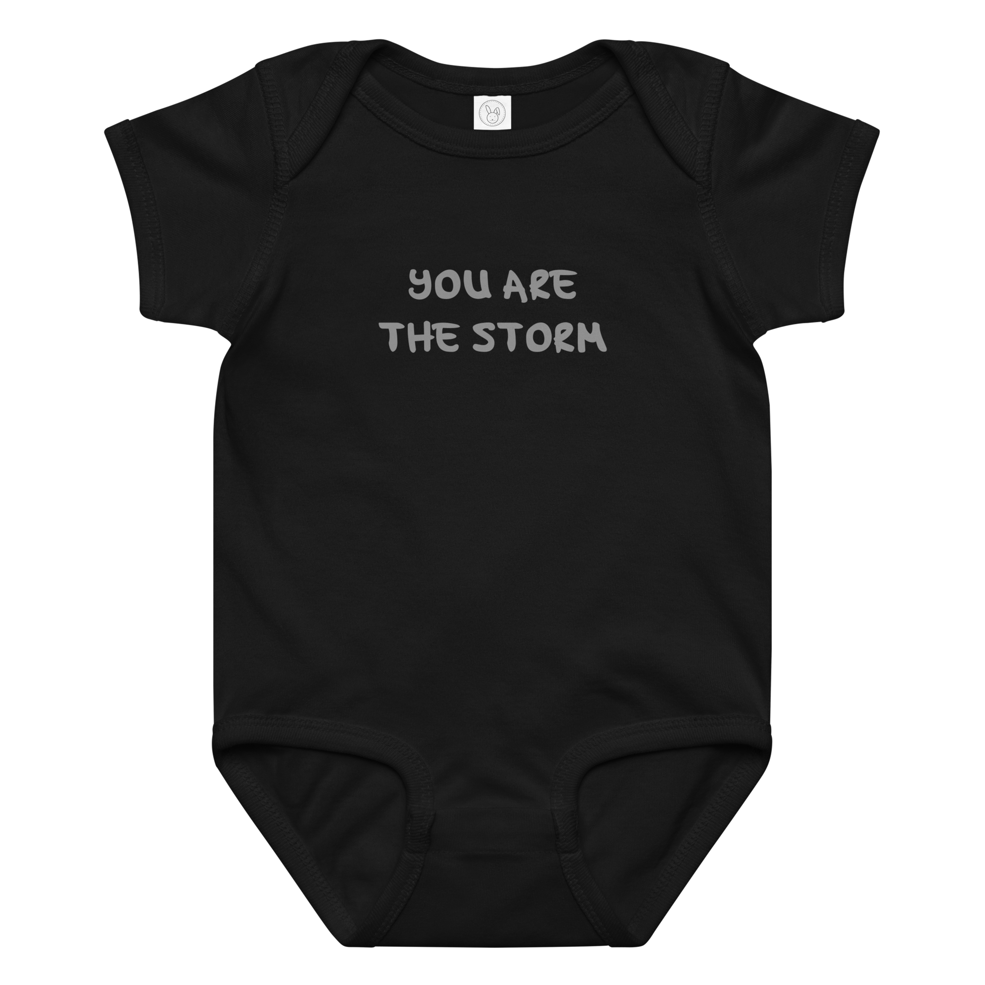 "You are the storm" printed on a black baby jersey bodysuit laying on a flat surface amongst other clothes
