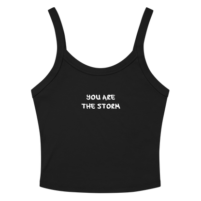 "You are the storm" printed on a solid black blend women's micro-rib tanktop laying on a flat surface amongst sunglasses and shorts