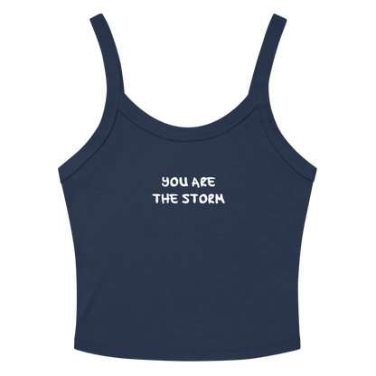"You are the storm" printed on a solid navy blend women's micro-rib tanktop laying on a flat surface amongst sunglasses and shorts