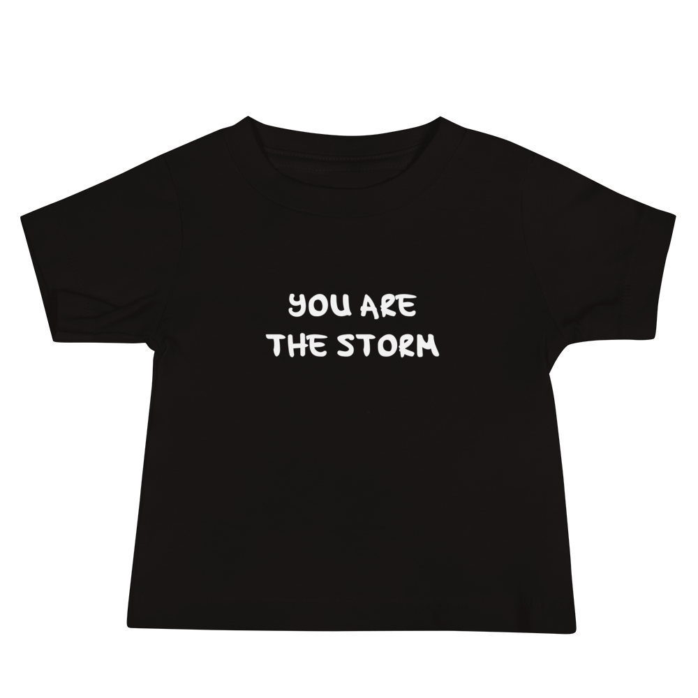 "You are the storm" printed on a black baby jersey short sleeve tee laying on a flat surface