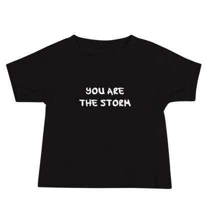 "You are the storm" printed on a black baby jersey short sleeve tee laying on a flat surface