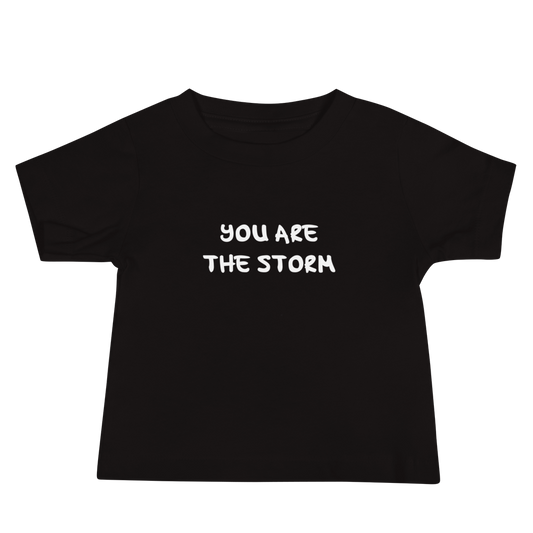 "You are the storm" printed on a black baby jersey short sleeve tee laying on a flat surface