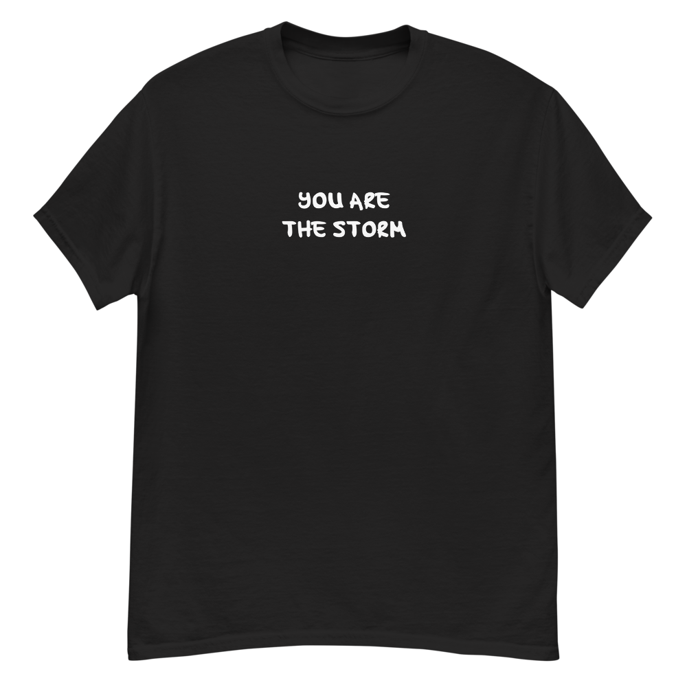 "You are the storm" printed on a black unisex classic tee laying on a flat surface
