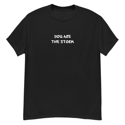 "You are the storm" printed on a black unisex classic tee laying on a flat surface