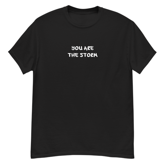 "You are the storm" printed on a black unisex classic tee laying on a flat surface