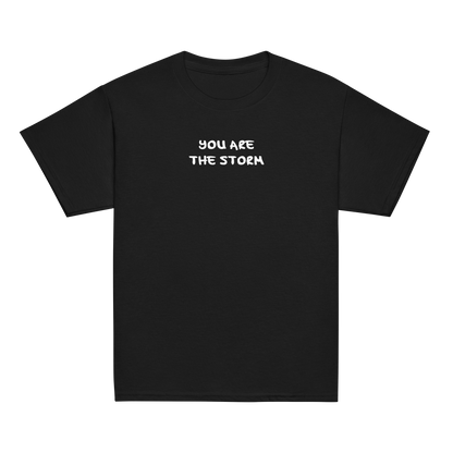 "You are the storm" printed on a black youth classic tee laying on a flat surface