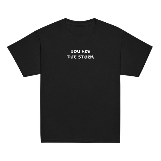 "You are the storm" printed on a black youth classic tee laying on a flat surface
