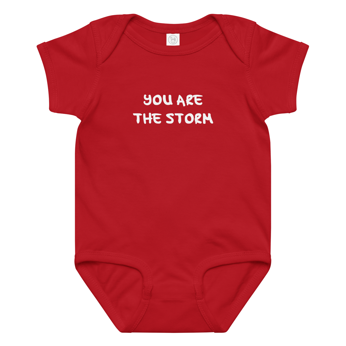 "You are the storm" printed on a red baby jersey bodysuit laying on a flat surface amongst other clothes