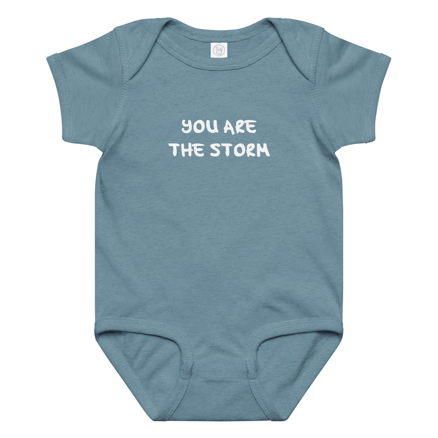"You are the storm" printed on a vintage indigo baby jersey bodysuit laying on a flat surface amongst other clothes