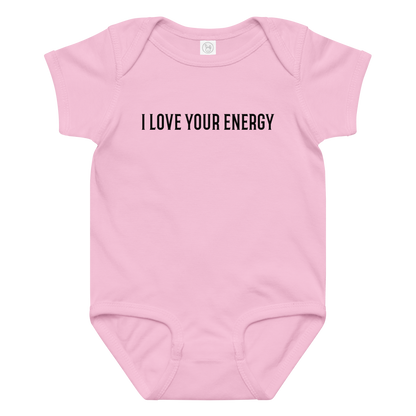 "I love your energy" printed on a pink baby jersey bodysuit laying on a flat surface amongst other clothes