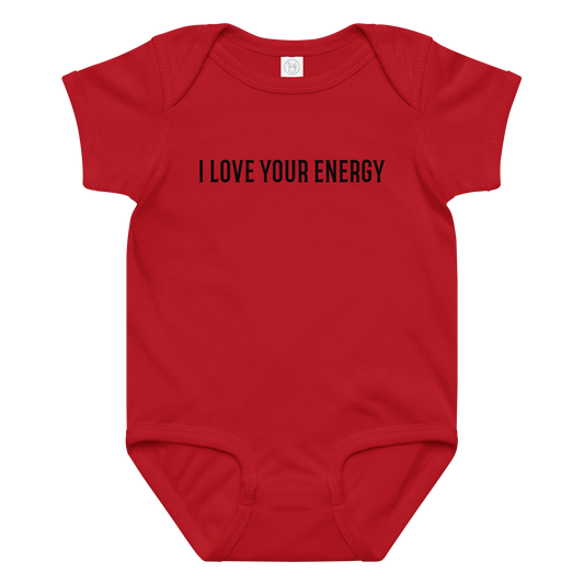 "I love your energy" printed on a red baby jersey bodysuit laying on a flat surface amongst other clothes