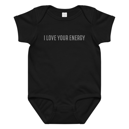 "I love your energy" printed on a black baby jersey bodysuit laying on a flat surface amongst other clothes