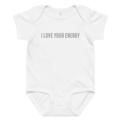 "I love your energy" printed on a white baby jersey bodysuit laying on a flat surface amongst other clothes