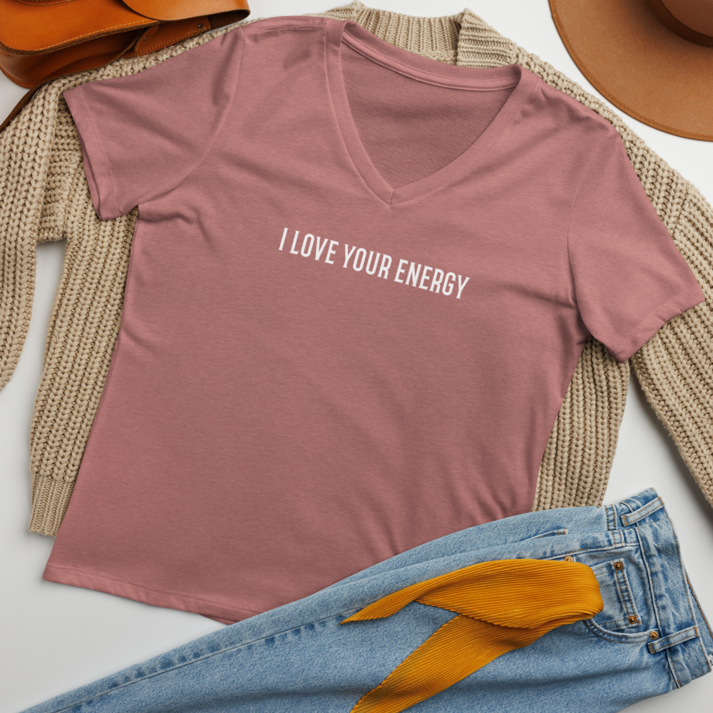"I love your energy" printed on a heather mauve women's relaxed v-neck t-shirt laying on a flat surface amongst other clothes