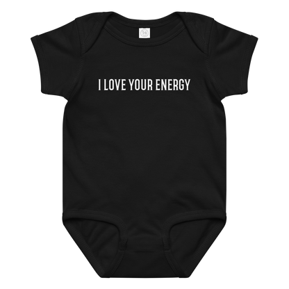 "I love your energy" printed on a black baby jersey bodysuit laying on a flat surface amongst other clothes